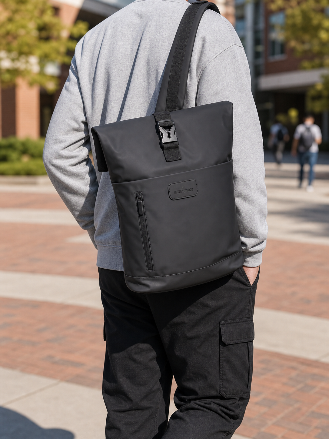 Black expandable roll-top laptop backpack worn over one shoulder on campus