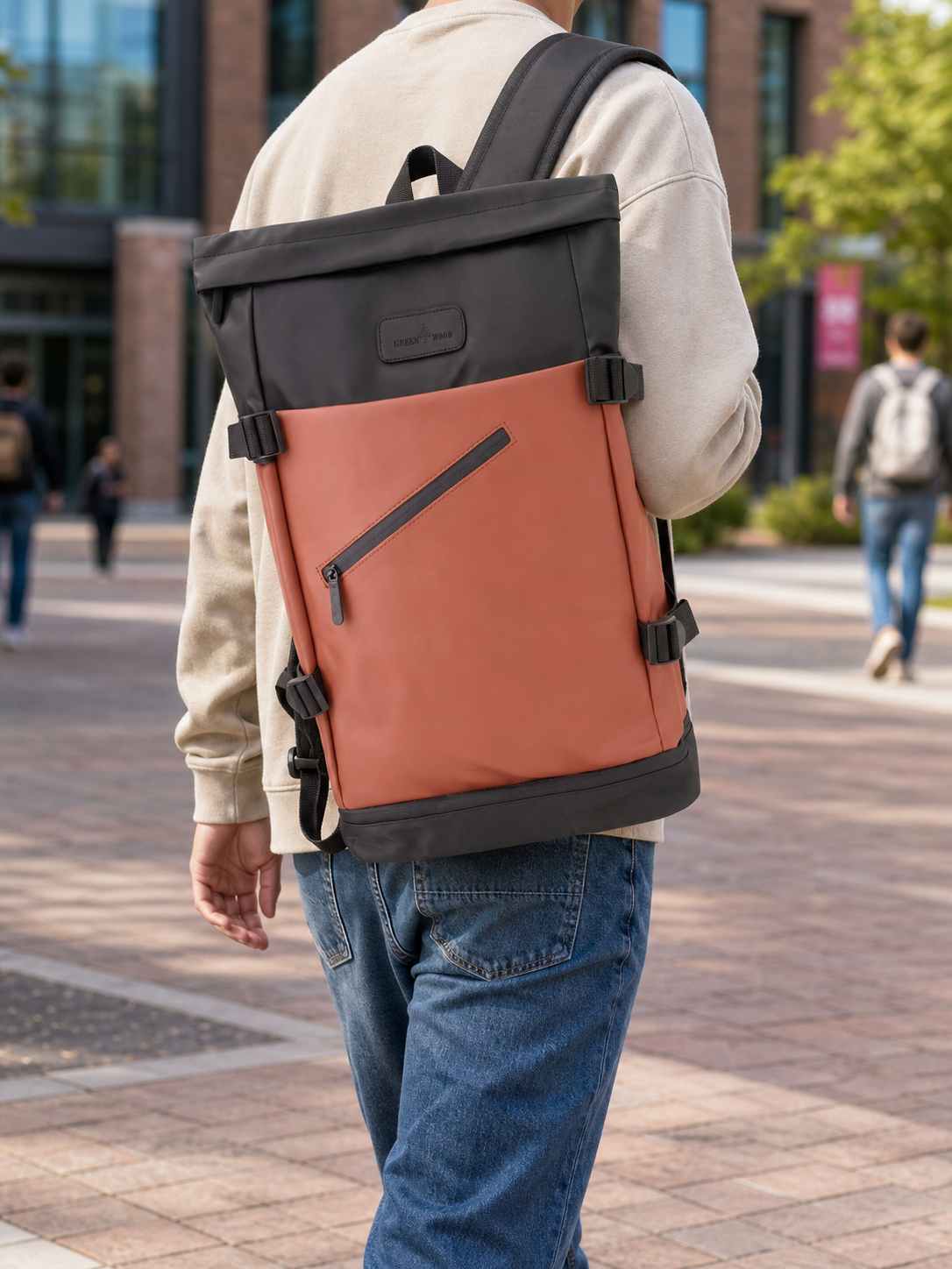 Tan roll-top laptop backpack worn over one shoulder on campus