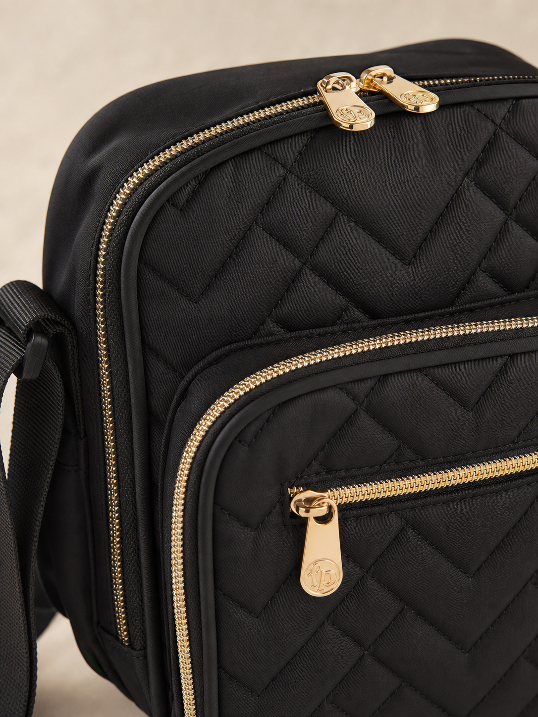Detail of the quilted material and gold-tone zipper on the bottle bag