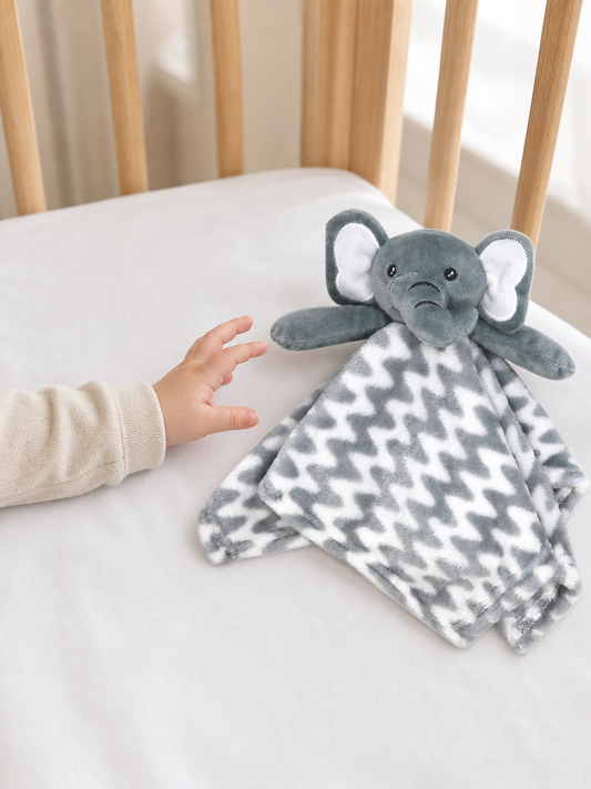 Baby's hand holding the grey elephant lovey from the Nest Starter Set