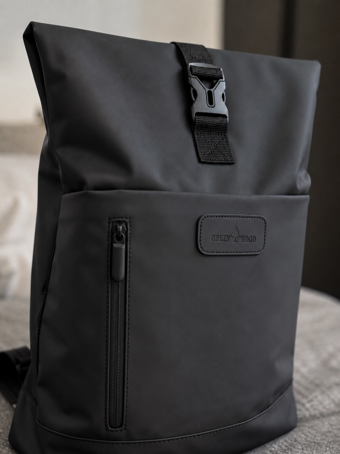 Zipper and buckle hardware detail on the black roll-top backpack