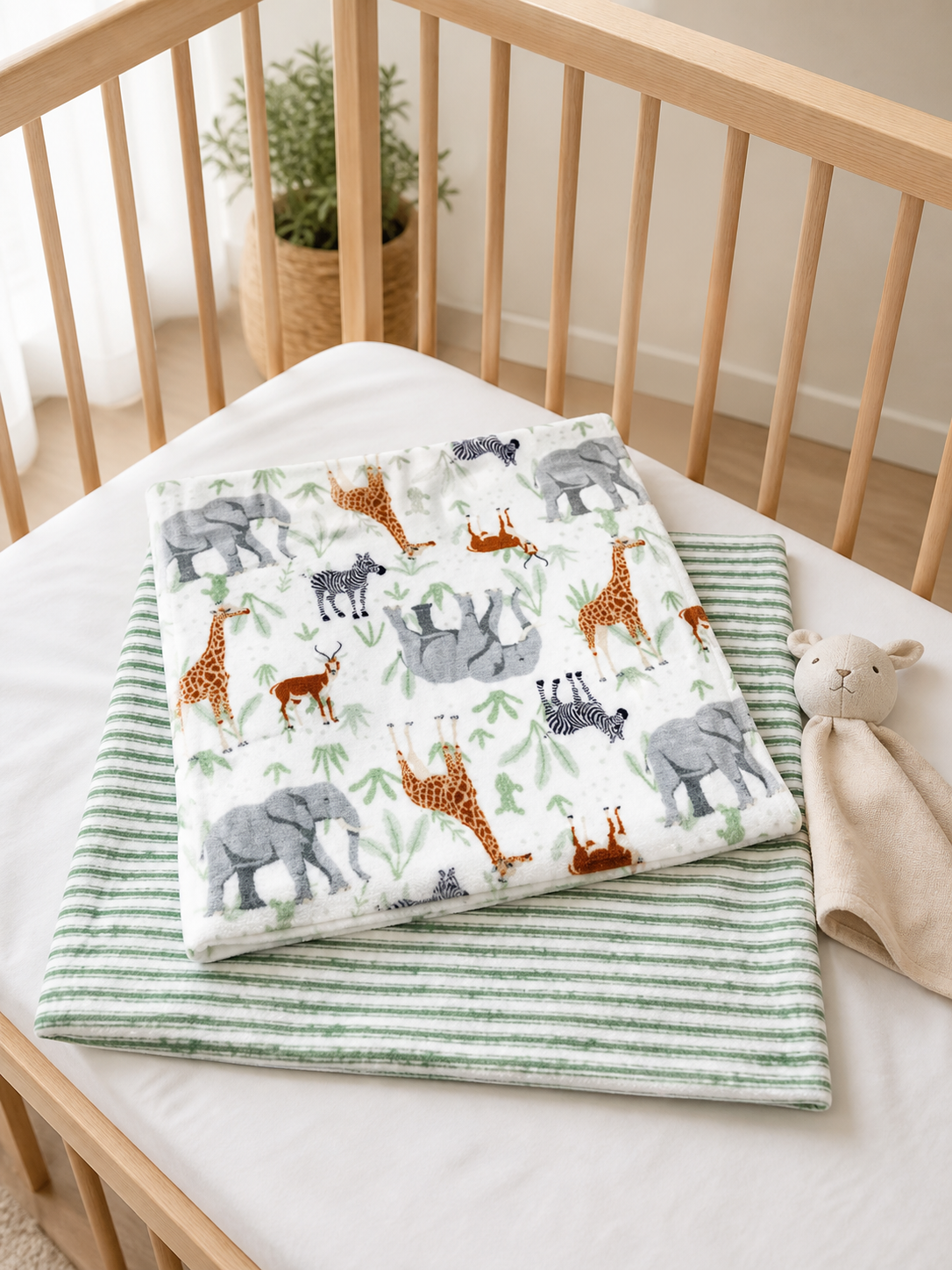 Sage safari blanket set in a crib with a plush lovey