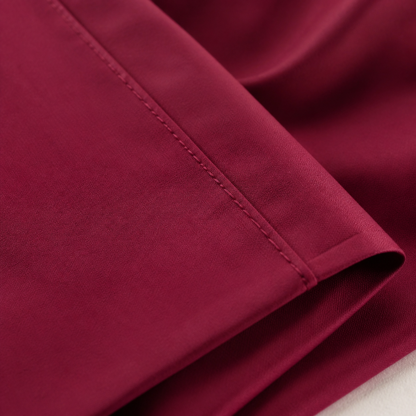 Close-up of the burgundy 600 thread count percale weave and stitched hem