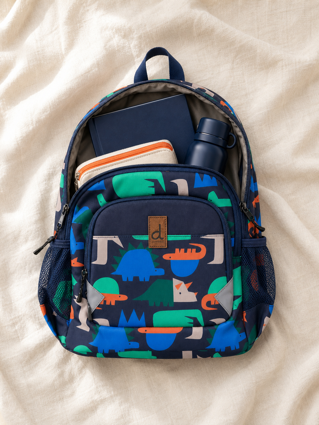 Flat lay of the navy dinosaur backpack with school supplies