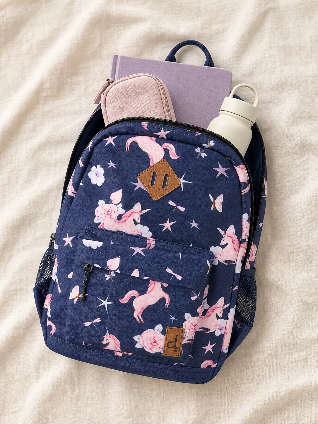 Flat lay of the navy unicorn backpack with school supplies