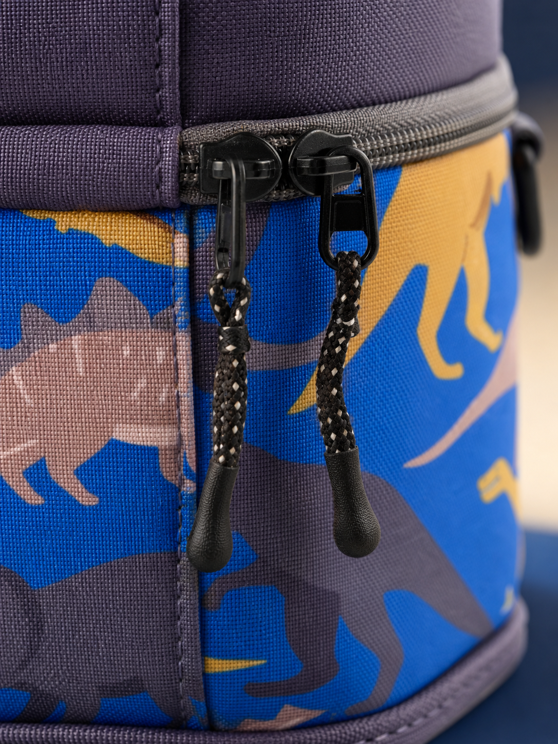 Macro detail of the zipper on the blue dinosaur lunch box