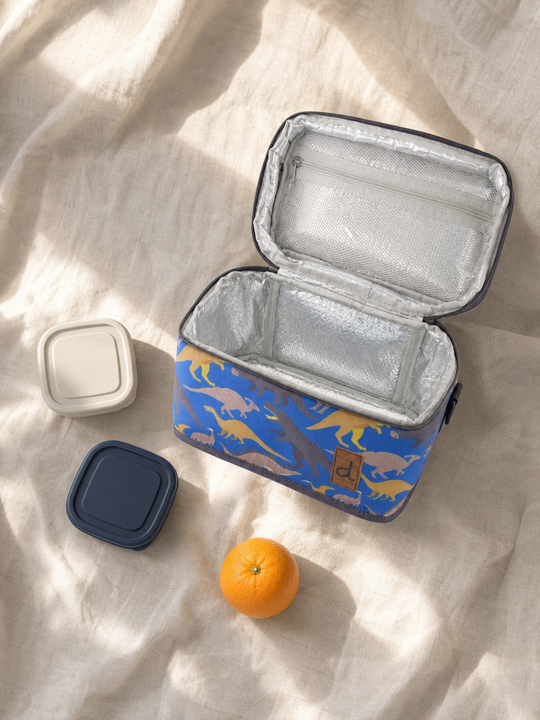 Flat lay of the blue dinosaur lunch box with school supplies