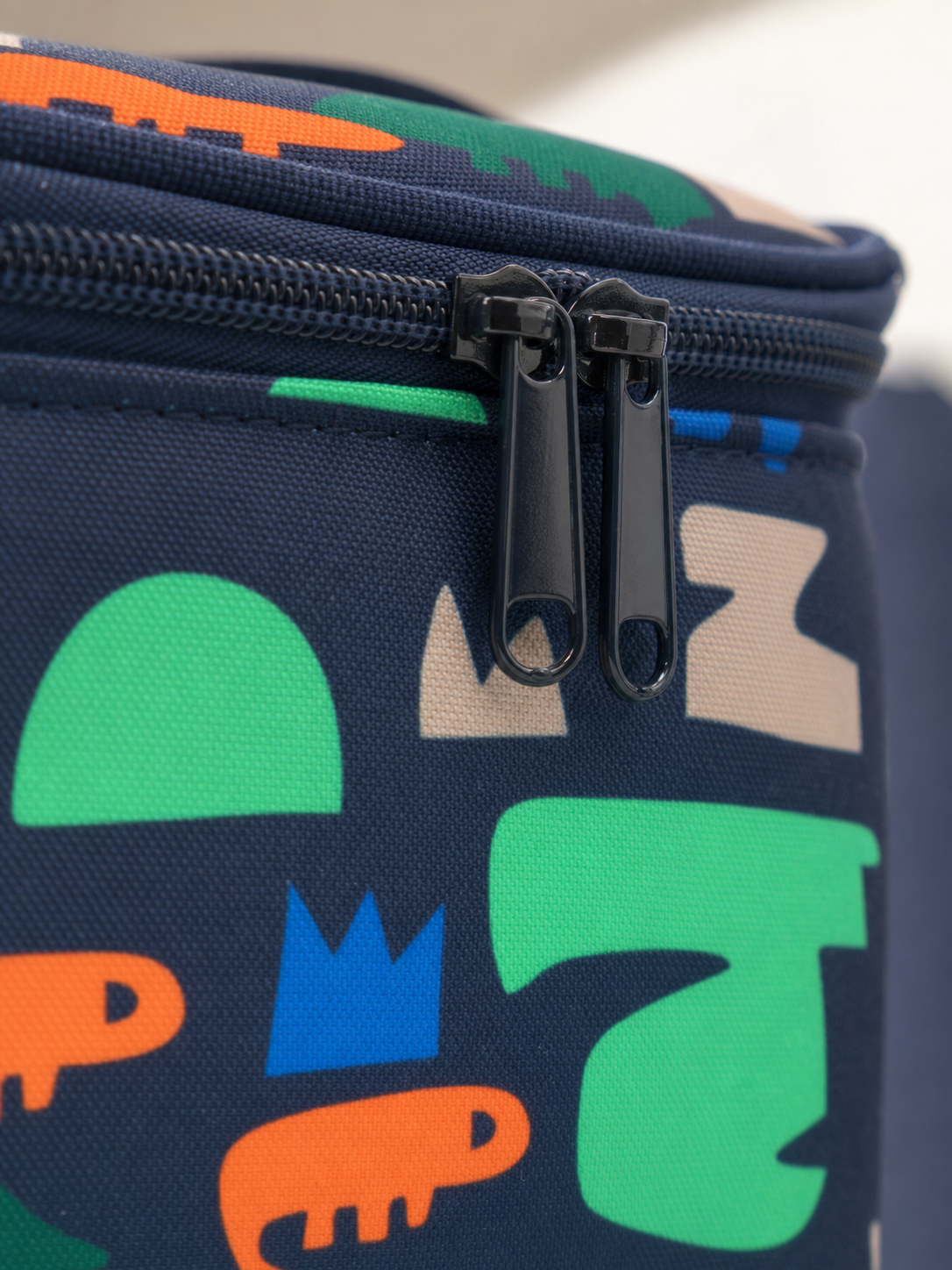 Macro detail of the zipper on the navy dinosaur lunch box