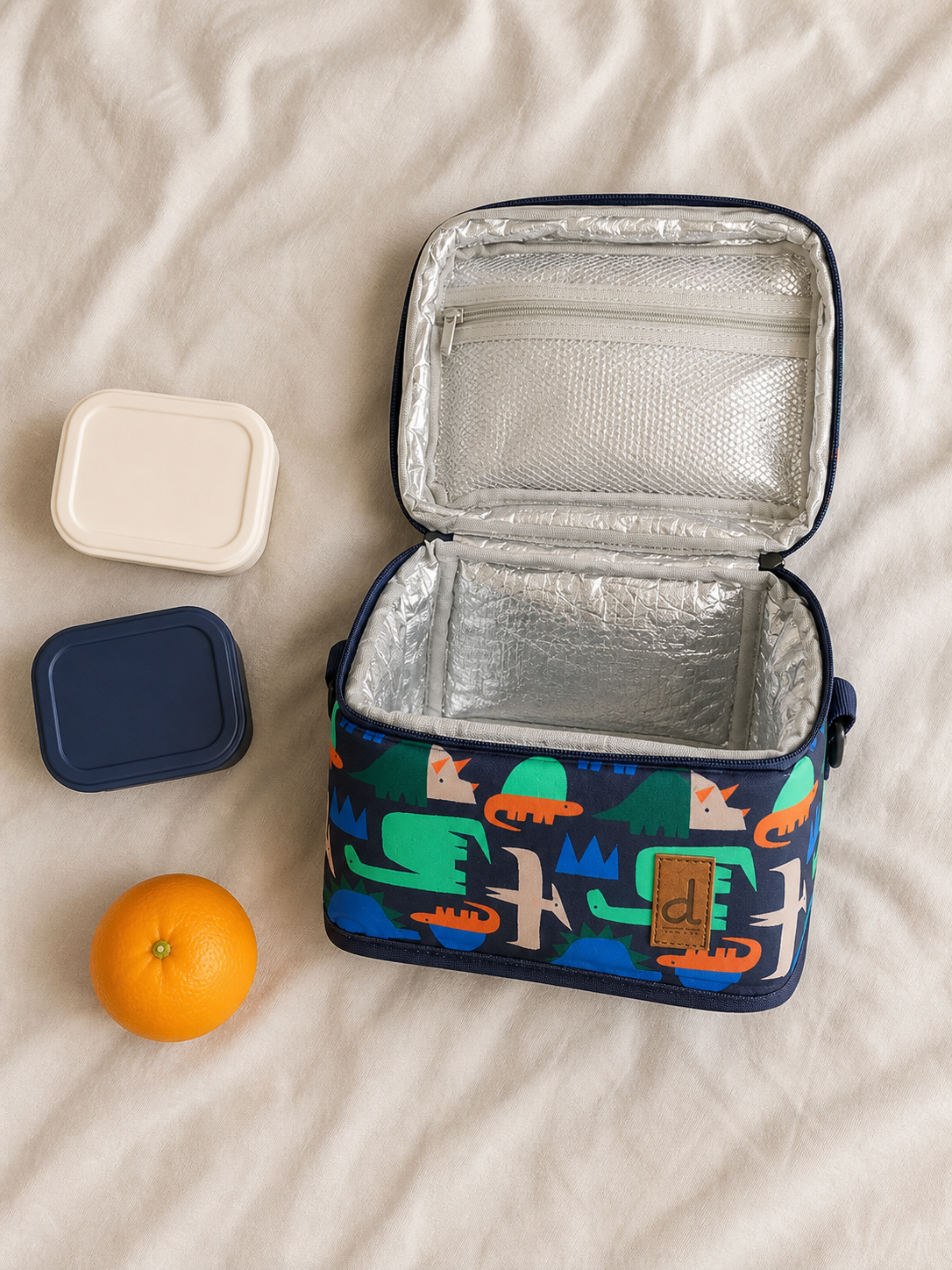 Flat lay of the navy dinosaur lunch box with school supplies