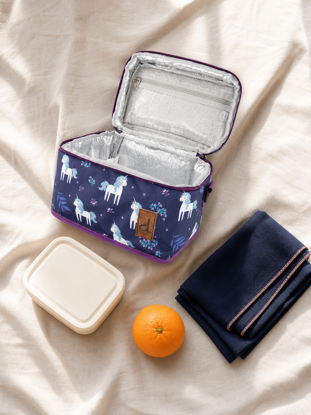 Flat lay of the unicorn print lunch box with school supplies